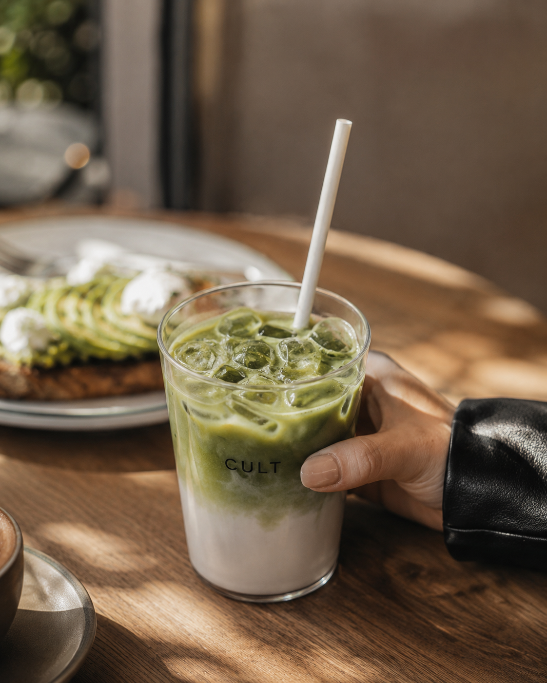 Un matcha latte glac&eacute; dans un verre CULT Paris sur une table de caf&eacute;.