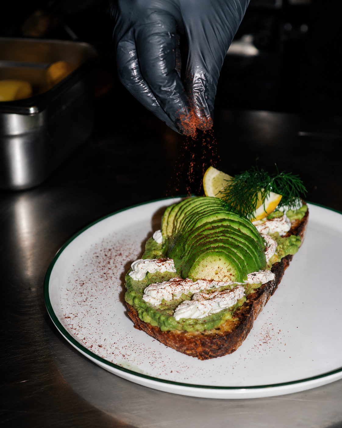 Un chef qui termine un toast &agrave; l&rsquo;avocat avec sumac et aneth.